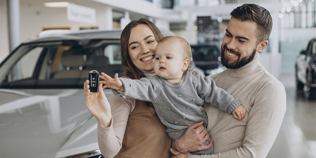 Família feliz em concessionária com carro novo