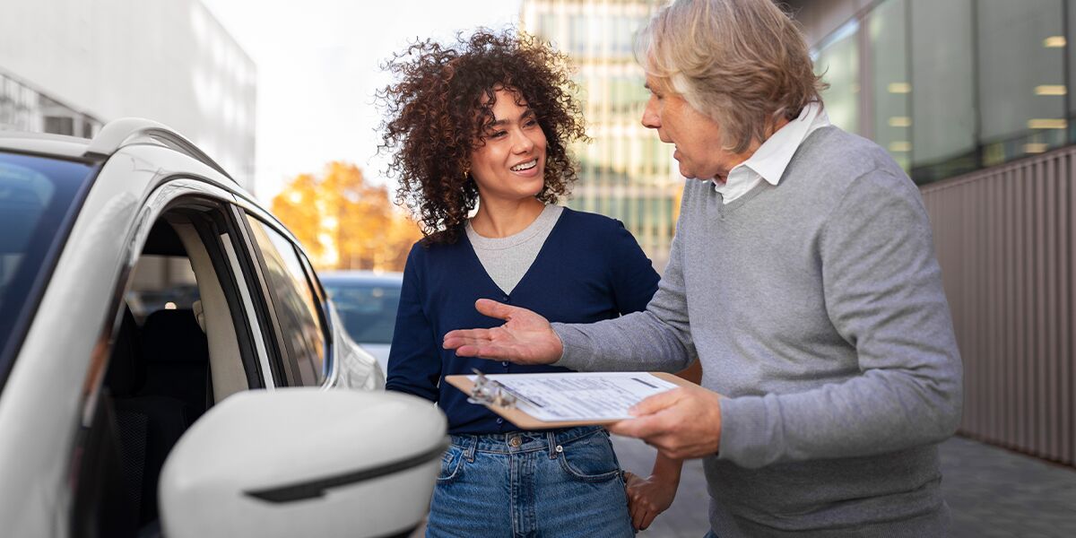 Mulher sorri enquanto conversa com homem em estacionamento
