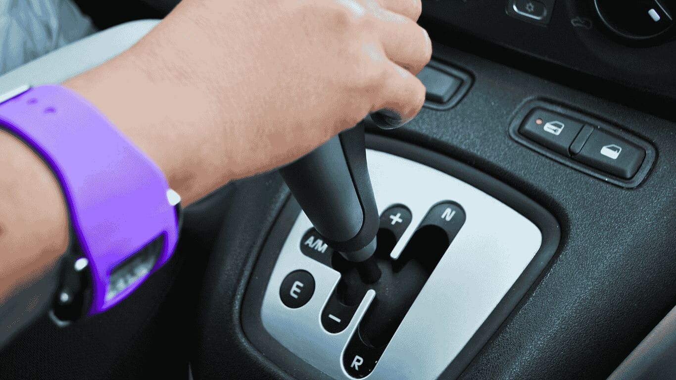 Mão segurando câmbio automático de carro