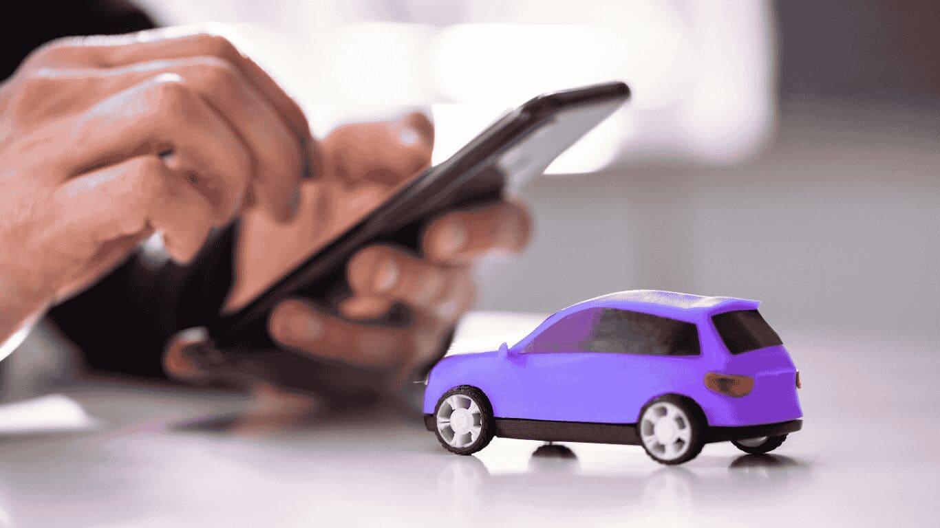 Pessoa usando celular com carro de brinquedo roxo ao lado