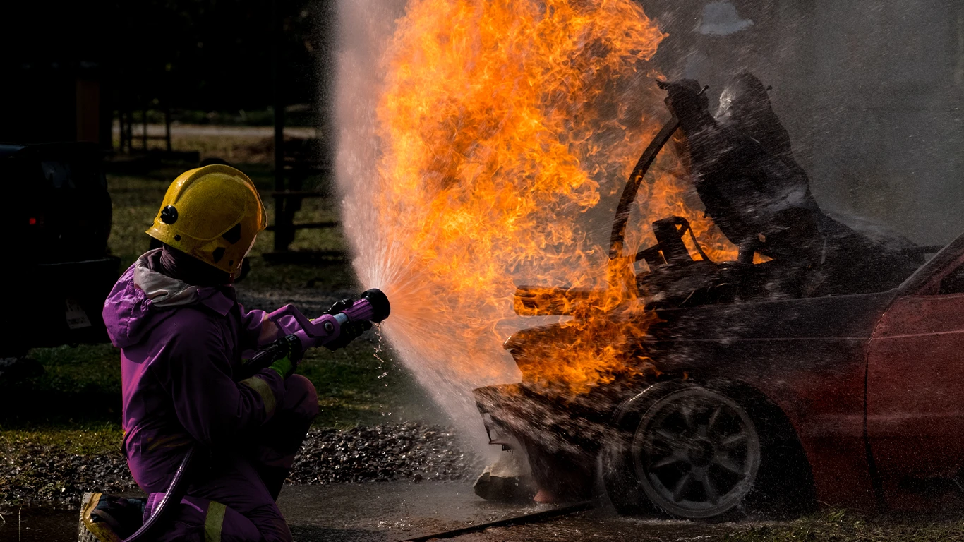 Bombeiro apagando fogo em carro queimando