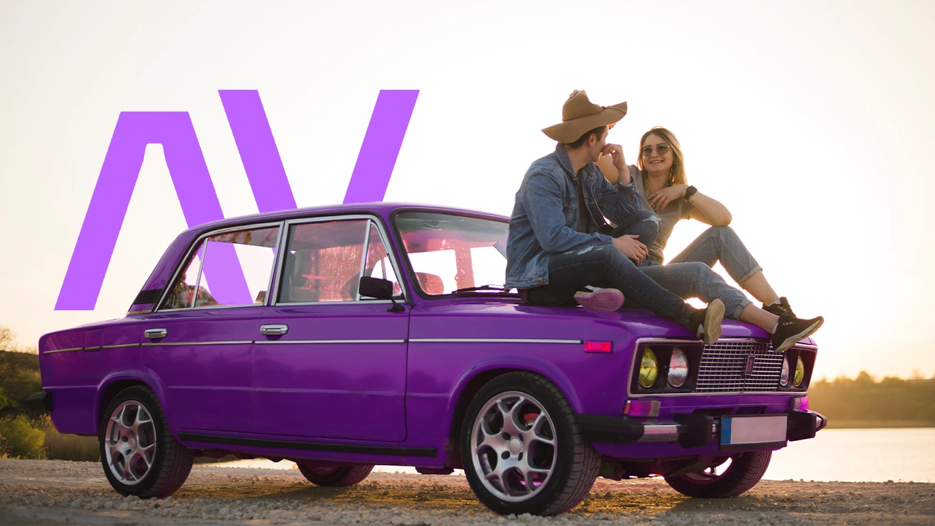 Casal relaxando em carro roxo ao pôr do sol